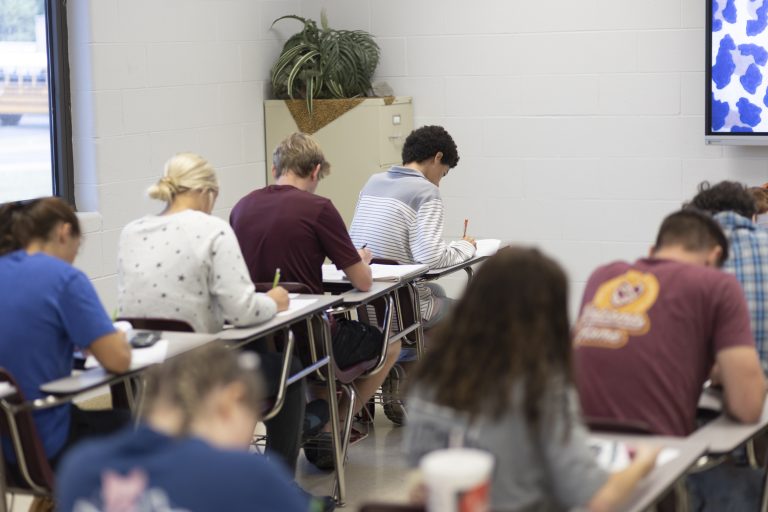 Students writing at desk.