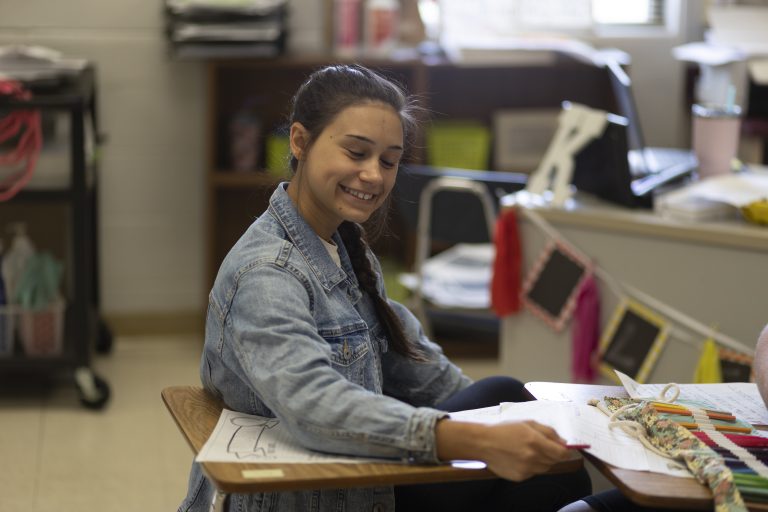 Female student smiling at desk.