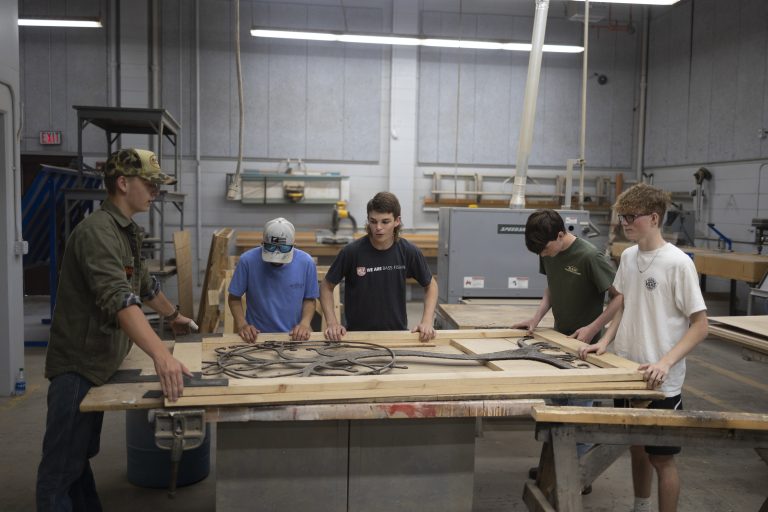 A group of students practicing wood skills in shop class.