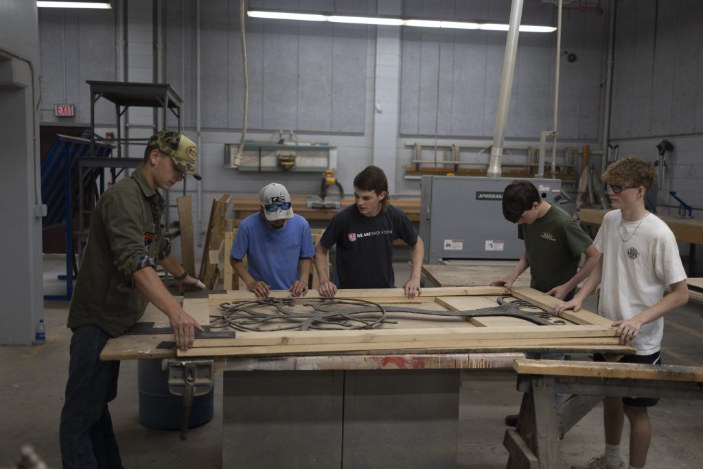 A group of students working with wood on a table.